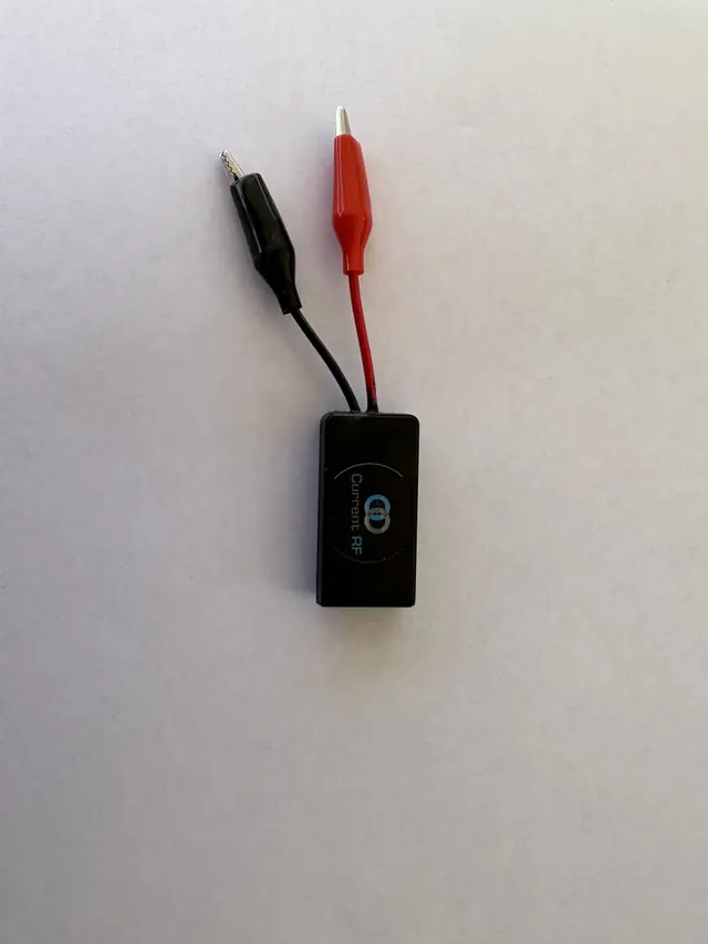 A single Current RF clip-lead Mileage Booster module on a grey ground